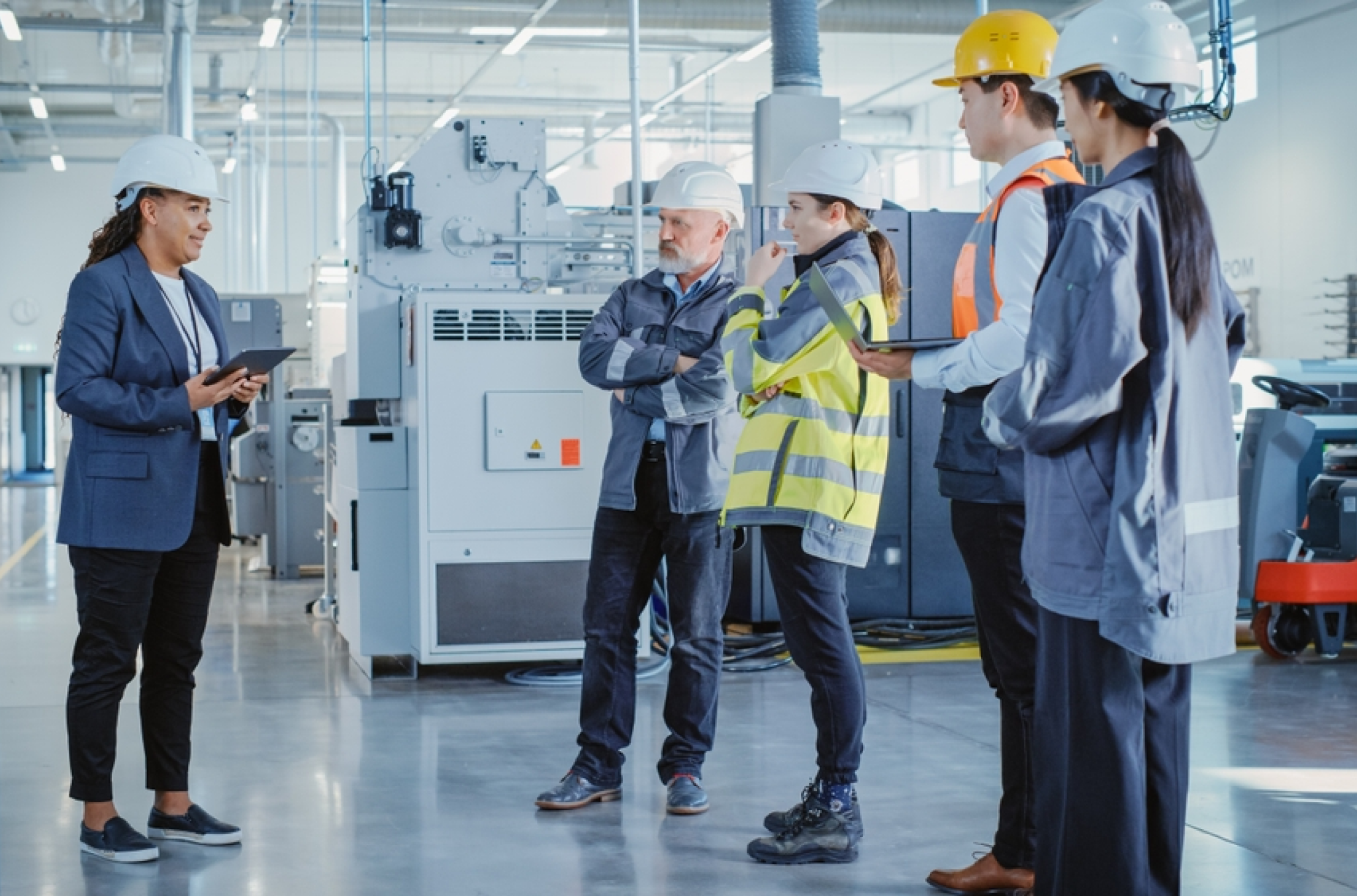 Manufacturing employees standing around the work floor, discussing how they will build shift schedules together